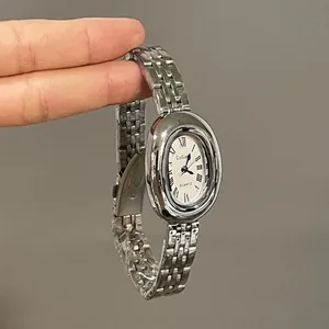 Macro detail of silver oval quartz watch with Roman numerals and steel mesh band