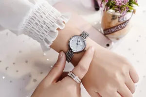 Détail d'une montre argentée pour femme avec cadran scintillant et bracelet perlé