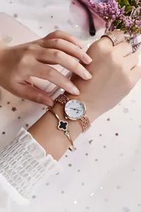 Détail d'une montre élégante en or rose avec bracelet trèfle et bague diamantée