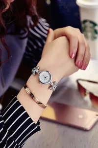 Close-up of women's silver quartz watch with rhinestone bow bracelet and gold screw bangle