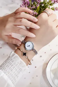 Close-up of elegant silver quartz watch paired with a black clover bangle on a woman's wrist