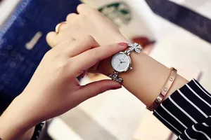 Detail of floral diamond strap watch paired with rose gold bracelet on a woman wrist