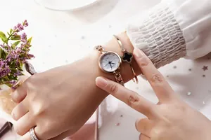 Close-up of rose gold quartz watch and matching black four-leaf clover bracelet set