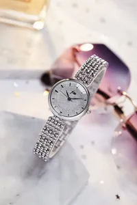Vue macro d'une montre argentée pour femme avec cadran scintillant et bracelet perlé