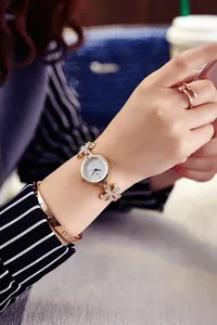 Close-up of rose gold fashion watch featuring flower crystal accents on a female wrist