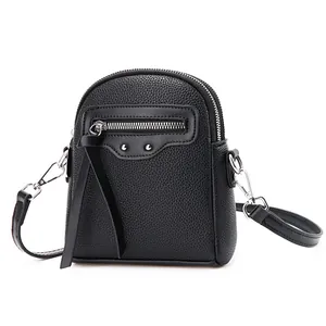 Sac bandoulière noir minimaliste en cuir grainé avec double zip et détails de glands