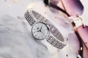 Détail d'une montre à quartz argentée pour femme avec cadran scintillant sur marbre blanc