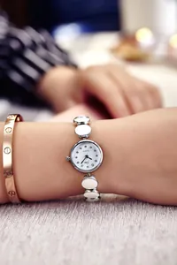 Nahaufnahme der Damen-Quarzuhr mit silbernem Metallkettenarmband und weißen Emaillestücken