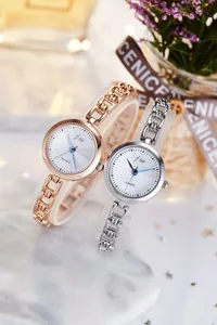 Detail of rose gold and silver quartz watches with fine chain straps on marble base