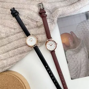 Detail of rose gold watches with black and burgundy leather straps on a knit sweater