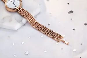 Détails du bracelet perlé en or rose et du cadran blanc avec aiguilles bleues de montre