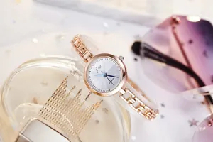 Rose gold quartz watch featuring a sunray dial and chain strap on a stylish lifestyle background