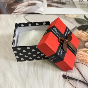 Elegant red and black watch gift box with ribbon bow on a soft white faux fur background