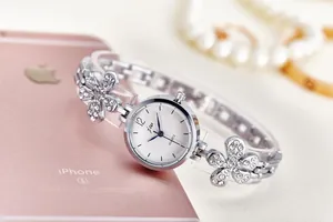 Close-up of a women's silver quartz watch with floral rhinestone bracelet on a phone back