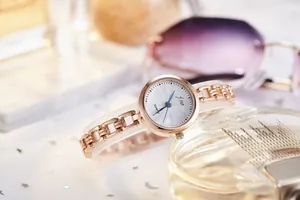 Macro detail of fashionable rose gold chain watch featuring a white sunburst dial and blue hands
