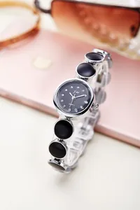 Detailansicht der silbernen Armbanduhr mit schwarzen Emaille-Anhängern und Quarz-Zifferblatt