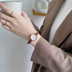 Elegant rose gold women's watch with a slim brown leather strap and white textured dial