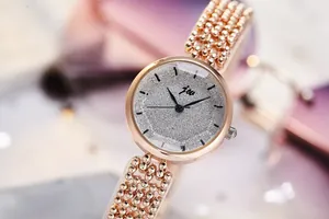 Gros plan d'une montre femme en or rose avec cadran pailleté et bracelet à perles chic