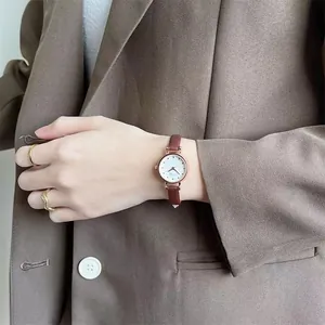 Detailed view of a vintage lady's watch with rose gold case and dark brown leather strap