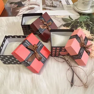 Three elegant watch gift boxes with silk bows and heart patterns on soft plush background