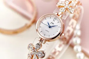 Detailed close-up of rose gold quartz watch featuring floral links and crystal accents