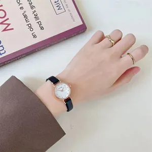 Close-up of minimalist women's watch with rose gold case and black slim leather strap