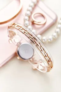 Detail of rose gold metal chain watch strap with elegant clover charm and metallic luster