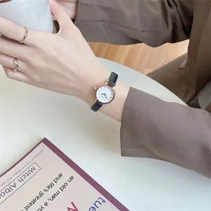 Women's minimalist watch with black leather strap and matching gold rings