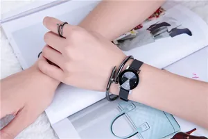 Close-up of black watch set featuring nail-shaped bracelet and ring on white plush rug