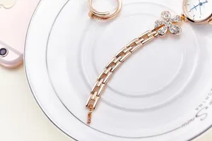 Close-up of rose gold watch with rhinestone clover design on a white ceramic plate