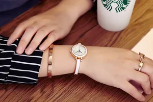Montre à quartz en or rose avec bracelet à vis et bague coeur portée au poignet