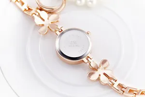 Macro shot of stainless steel watch back and rose gold floral bracelet band