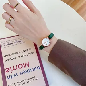 Detail shot of a dark green leather strap watch with rose gold case and gold rings