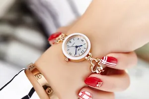 Close-up of women's rose gold quartz watch with floral bracelet links and white bezel