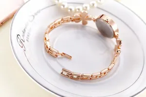 Close-up of rose gold fashion watch with floral diamond charm on metal chain strap