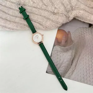 Detailed close-up of a vintage green leather strap watch with rose gold case and white dial