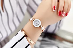 Dettaglio dell'orologio al quarzo oro rosa con quadrante bianco e maglia floreale