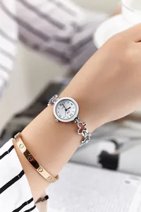 Detail of a silver flower-shaped link bracelet quartz watch worn on a wrist in elegant setting