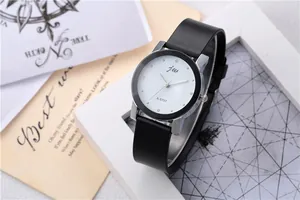Detail shot of minimalist silver watch with black leather strap and white dial