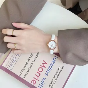 Close-up of a delicate rose gold women's watch with white leather strap and ring accents