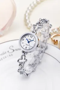 Detail of silver quartz watch with clover hollow band on a white porcelain dish