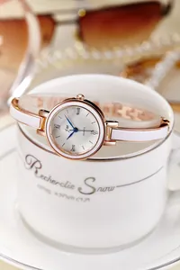 Détail d'une montre à quartz or rose avec aiguilles bleues sur une tasse à café
