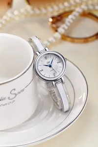 Détail d'une montre à quartz argentée avec bracelet en émail blanc et aiguilles bleues