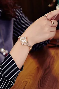 Detail of rose gold square watch with crystal-encrusted bezel on a woman's wrist