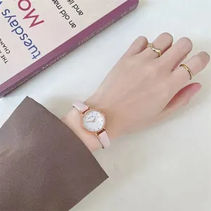 Close-up of rose gold ladies watch with pink leather strap and gold ring accessories