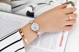 Dettaglio di un elegante orologio al quarzo con cinturino a fiori bianchi su polso femminile