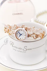 Detail of quartz watch featuring butterfly-shaped metal chain links on a ceramic cup