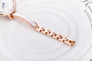 Macro d'un bracelet doré rose avec émail blanc et aiguilles bleues sur le cadran
