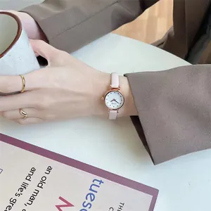 Close-up of elegant rose gold watch with pink leather strap and small white dial on wrist
