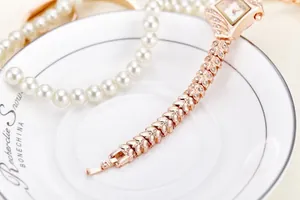 Macro detail of rose gold rhinestone watch band with wheat shaped links and crystal accents